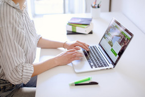Work on laptop Student typing on laptop, books and pens next to it.